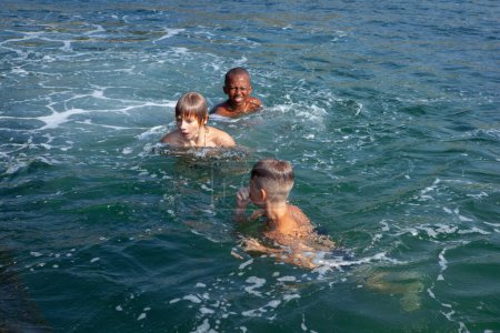 Téléchargez les photos : Les enfants nagent dans la mer pendant les vacances d'été - en image libre de droit