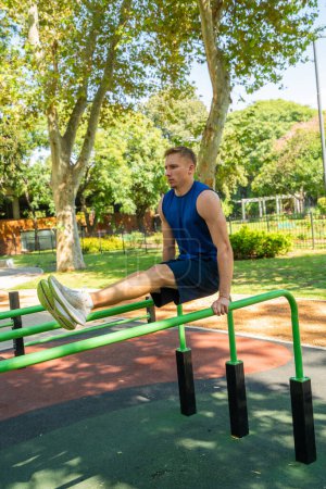 Photo for Young guy athlete exercising on sports equipment in the park - Royalty Free Image