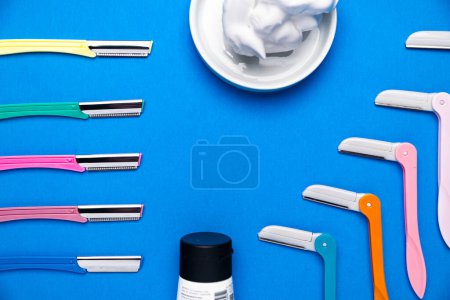 Photo for Colored razor shavers, on a blue background. image of beautiful multicolored razor shavers and shaving foam. copy space for text. - Royalty Free Image