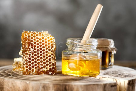 Honey jar with dipper and honeycomb on wooden stump