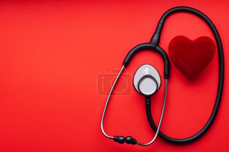 Photo for Stethoscope and red heart on a red background. View from above. Space for text. - Royalty Free Image