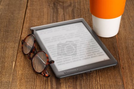 Téléchargez les photos : E-book reader et lunettes sur une table en bois. - en image libre de droit