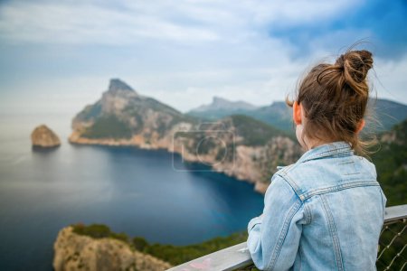 A little girl gazing at a breathtaking view from Mirador de El Colomer in Mallorca, evoking a sense of awe and tranquility