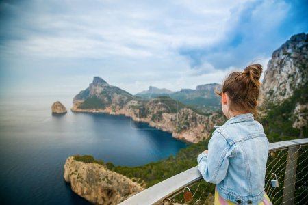 Téléchargez les photos : Vue arrière d'une petite fille regardant une belle vue sur le cap Formentor depuis Mirador de El Colomer à Majorque - en image libre de droit