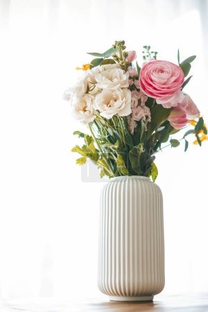 Ein bunter Blumenstrauß in verschiedenen Formen und Größen ziert eine gerippte weiße Vase