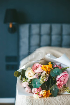 A colorful bouquet of flowers on a neatly made bed, set against the backdrop of a bedroom, creating a scene of elegance and tranquility