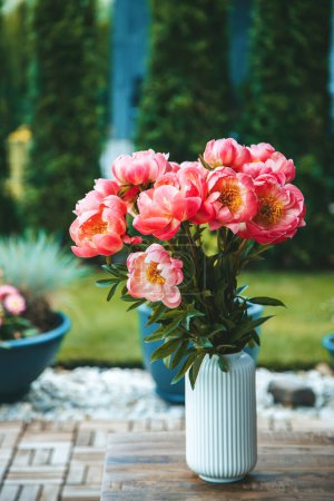 Téléchargez les photos : Un bouquet de pivoines roses vibrantes, aux pétales luxuriants, dans un vase blanc - en image libre de droit