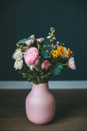 Téléchargez les photos : Un beau bouquet de fleurs assorties placées dans un vase rose sur un fond sombre, créant un contraste visuellement agréable et soulignant les couleurs vibrantes des fleurs - en image libre de droit