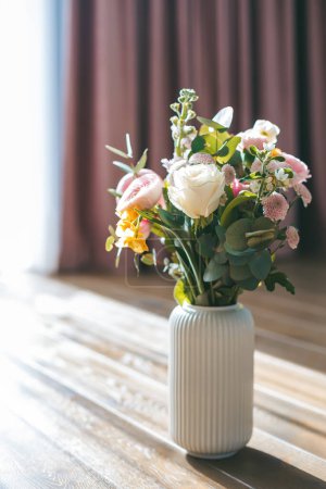 Téléchargez les photos : Un bouquet de charme avec un assortiment de roses blanches, de ranunculus roses et de fleurs jaunes, disposés dans un vase côtelé blanc - en image libre de droit