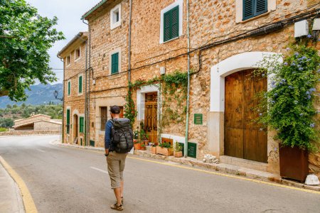 El turista caminando por la rústica calle del pueblo bordeado de encantadoras casas en Fornalutx, Mallorca, España