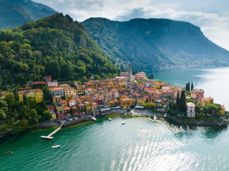 Foto de Volando sobre coloridas casas del pueblo de Varenna en el lago de Como, Italia. Foto aérea del casco antiguo de Varenna en la costa del Lago de Como. Verano turismo de lujo hito romántico viaje de luna de miel destino - Imagen libre de derechos