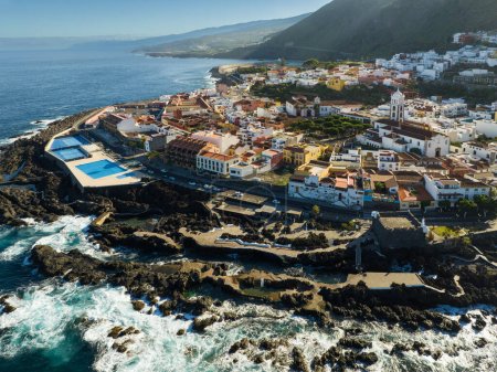 Flying over Garachico city center with colored houses. Aerial view of Old town of Garachico on island of Tenerife, Canary. Ocean shore and lava pools. Popular tourist destination, pearl of the Canary