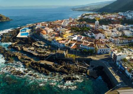 Flying over Garachico city center with colored houses. Aerial view of Old town of Garachico on island of Tenerife, Canary. Ocean shore and lava pools. Popular tourist destination, pearl of the Canary