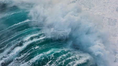 Téléchargez les photos : Slow motion aerial shot of powerful wave crashing on rocks. Sea or ocean big stormy surf clear turquoise water with foamy white texture. Aerial drone shot - en image libre de droit