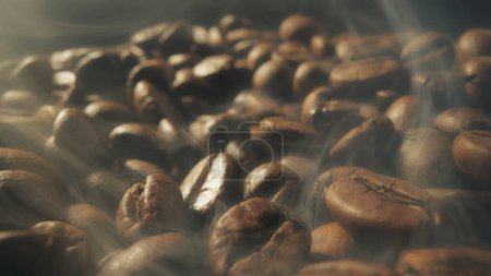 Slider shot of coffee beans during roasting. Dark roasted coffee beans with smoke. Smoke comes from fresh coffee seeds. Macro shot, 4K 2