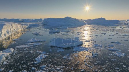 Strahlende Sonne lässt Teile des Eisbergs in Grönland schmelzen. Luftaufnahme von Eisbergstücken an sonnigen Tagen, globale Erwärmung und Klimaschutzkonzept