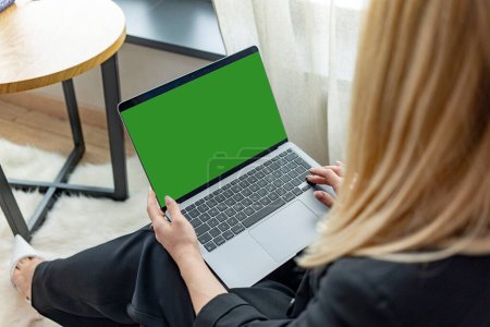 A young girl holds a laptop looking at a mock-up of a green computer screen online PC training. Close-up view over the shoulder. High quality photo
