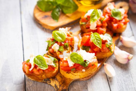 Photo for Classic italian bruschette grilled bread slices with tomato, basil and mozzarella cheese - Royalty Free Image