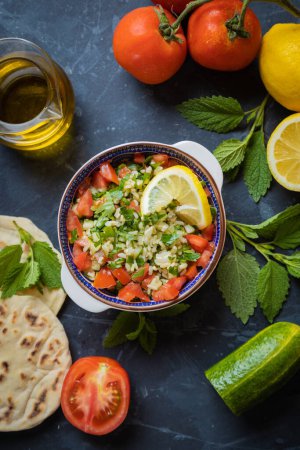 Foto de Ensalada de libanés con bulgur, perejil, pepino, tomate, limón y aceite de oliva - Imagen libre de derechos