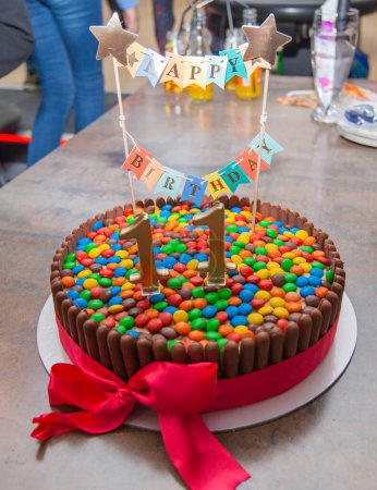 Photo for Delicious, multicolored birthday cake decorated with chocolate sticks and candy for a happy celebration. - Royalty Free Image