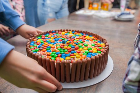 Foto de Delicioso pastel de cumpleaños multicolor decorado con palitos de chocolate y dulces para una feliz celebración. - Imagen libre de derechos