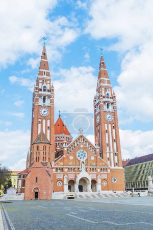 Téléchargez les photos : Une église votive en brique emblématique à Szeged, en Hongrie, avec une grande tour de l'horloge et une façade détaillée. Son importance historique se reflète dans son architecture impressionnante et son importance culturelle. - en image libre de droit