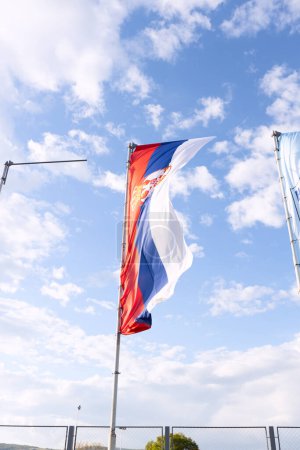 Foto de La bandera serbia ondeando orgullosamente contra el cielo azul es un signo de orgullo nacional y celebración del día de la independencia. - Imagen libre de derechos