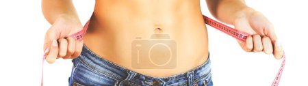 Photo for Slim Female with perfect healthy fitness body, measuring her thin waist with a tape measure. Caucasian young woman in jeans and T-shirt, over white background. Unrecognizable person.Diet and weight loss concept. - Royalty Free Image
