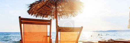 Téléchargez les photos : Vacances d'été et concept de voyage. Chaises de plage vides avec parasol sur le sable près de la mer avec lumière du soleil en arrière-plan
. - en image libre de droit