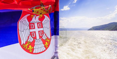 Photo for National flag of Serbia waving on wind at cruise ship, Danube river landscape and sky with clouds in background. - Royalty Free Image