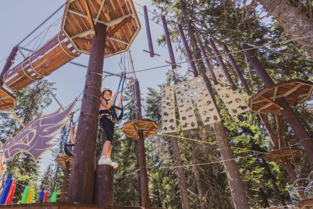 Téléchargez les photos : Jeune fille profitant d'une aventure passionnante tyrolienne dans la forêt. - en image libre de droit
