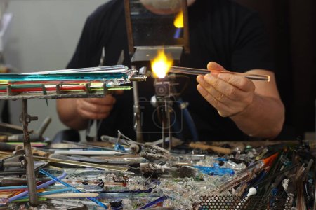 Foto de Vidriero mientras moldea el vidrio con una llama de muy alta temperatura en su taller artesanal en Venecia. Italia - Imagen libre de derechos