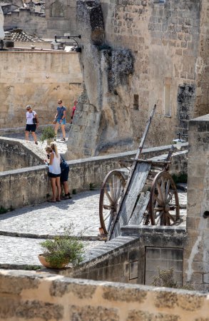 Photo for Matera, Italy - September 15, 2019: Tourists during a walk on Cobblestone street in the Sassi di Matera a historic district in the city of Matera. Basilicata. Italy - Royalty Free Image