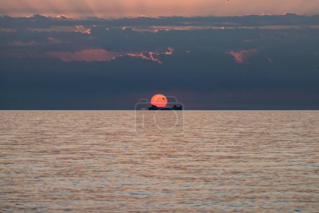 Merchant ship during sunrise over the Mediterranean Sea seen from the beach in Torremolinos. Costa del Sol, Spain