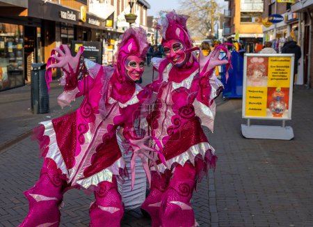 Téléchargez les photos : Noordwijkerhout, Pays-Bas - avril 21, 2023 : Femmes en costumes de conte de fées roses dans la rue à Noordwijkerhout avant la soirée illuminée Flower Parade Bollenstreek - en image libre de droit
