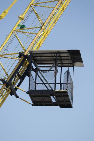 A majestic crane hoists its towering cargo against a vast sky, transporting its heavy burden across the outdoor construction site