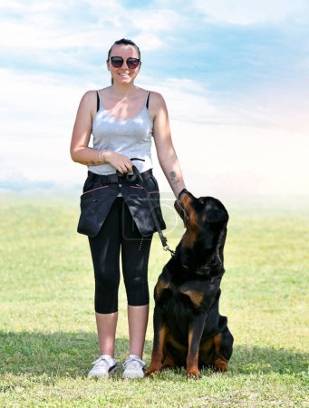 Foto de Mujer y rottweiler caminando en la naturaleza en verano - Imagen libre de derechos