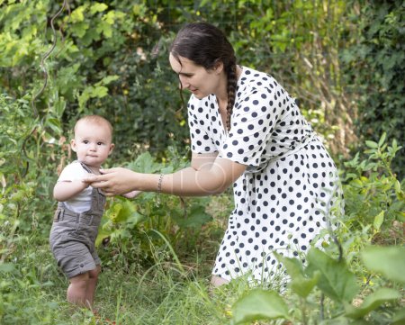 Photo for Young baby and mother gardening in her kitchen garden - Royalty Free Image