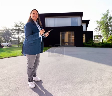 Photo for Estate agent woman in front of house background - Royalty Free Image