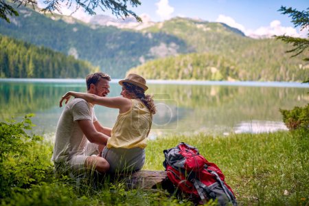 Téléchargez les photos : Jeune couple caucasien adulte s'embrassant au bord du lac avec une belle vue en face d'eux - en image libre de droit