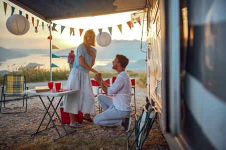 Photo for Romantic proposal outdoor in nature during the holiday in front of the camper - Royalty Free Image