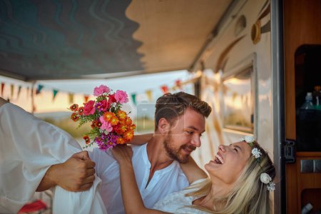 Téléchargez les photos : Gros plan d'un jeune homme barbu portant sa mariée à l'intérieur du camping-car, souriant, riant, juste marié - en image libre de droit