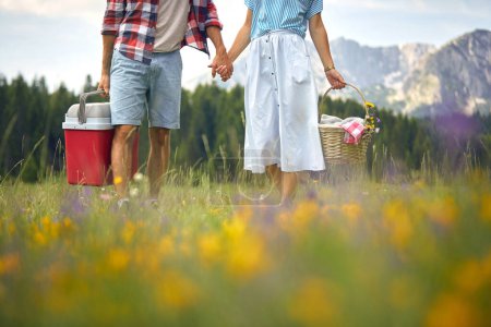 Photo for Young man and woman in love holding hands.Couple is holding picnic equipment. - Royalty Free Image