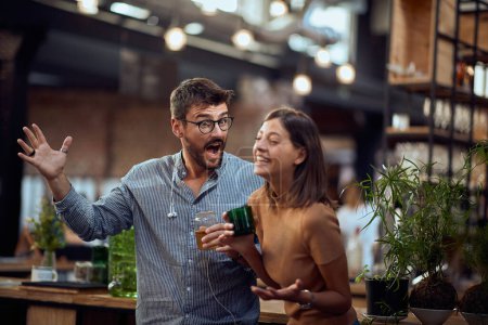 Photo for Young hipster man and woman in the bar having a great time, standing at the bar and having lively a conversation. - Royalty Free Image