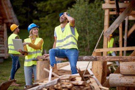 Photo for Builders are talking about a cottage project at a construction site in the forest on a beautiful day. Construction, building, workers - Royalty Free Image