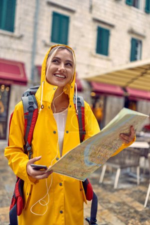 Photo for Young tourist in new city, traveling in rain with map. Young beautiful blonde woman smilling. Travel, city, lifestyle concept. - Royalty Free Image