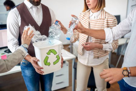 Photo for A group of employees is recycling the trash by collecting it in a bin in a pleasant atmosphere in the office. Employees, job, office - Royalty Free Image
