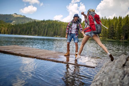 Foto de Excursionistas enamorados disfrutando de la naturaleza mientras juegan con el agua en el lago de la montaña. - Imagen libre de derechos