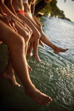 Téléchargez les photos : Jeunes gens balançant les jambes dans l'eau et appréciant - en image libre de droit