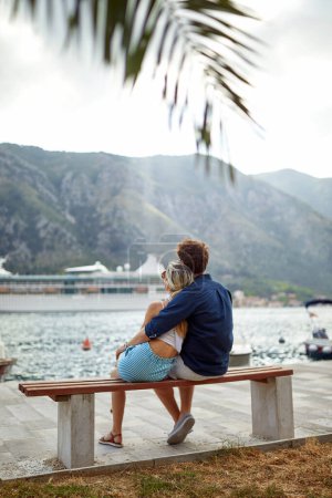 Foto de Pareja relajándose en el banco mirando al mar. Hermosa vista al mar disfrutando de libertad. Viajes, amor, unión, concepto de estilo de vida. - Imagen libre de derechos